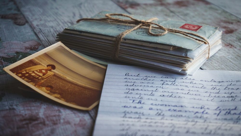 A bundle of old letters tied with twine beside a faded photograph